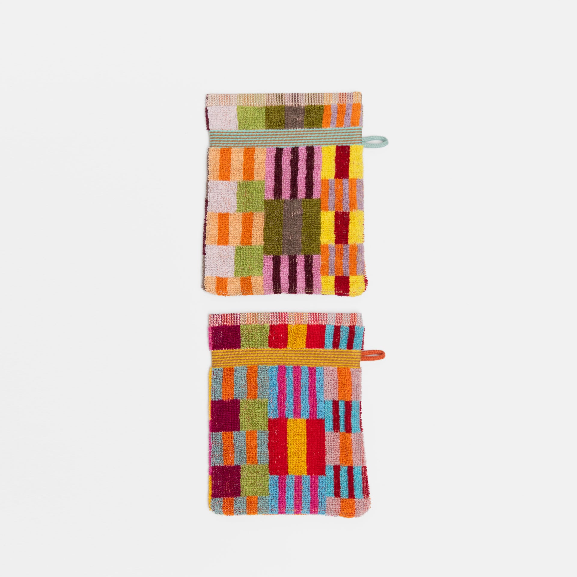 Set of two small, colorful cotton cloths from the Odds & Ends collection, each with a unique woven pattern made from leftover dyed yarns. Features a hanging loop, compact size (15 x 21 cm), and thick, durable fabric