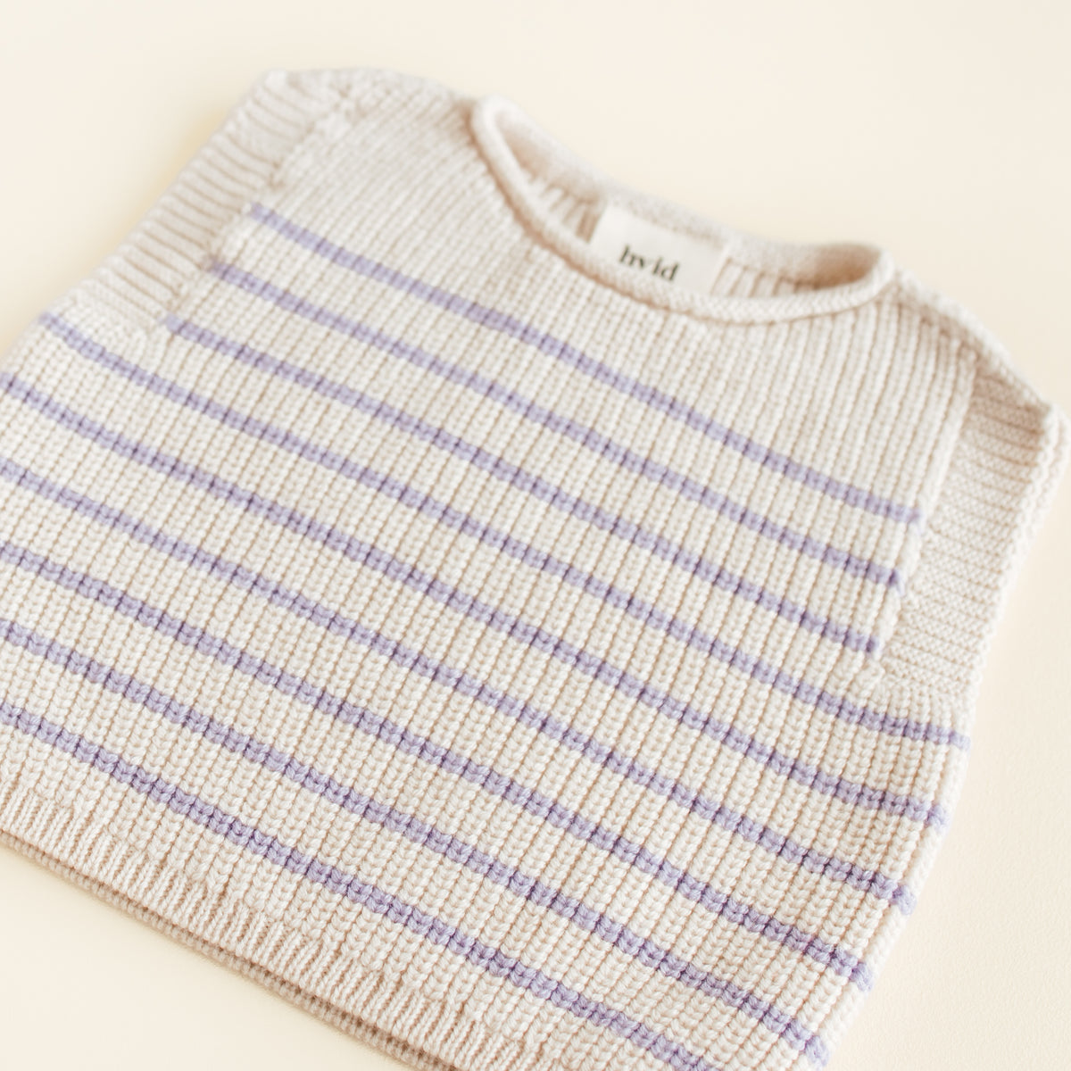 Hvid Vest Harvey in cream lila stripe, a seamless baby vest made from extra fine merino wool with a soft fisherman’s rib and elastic neckline, knitted in Belgium.