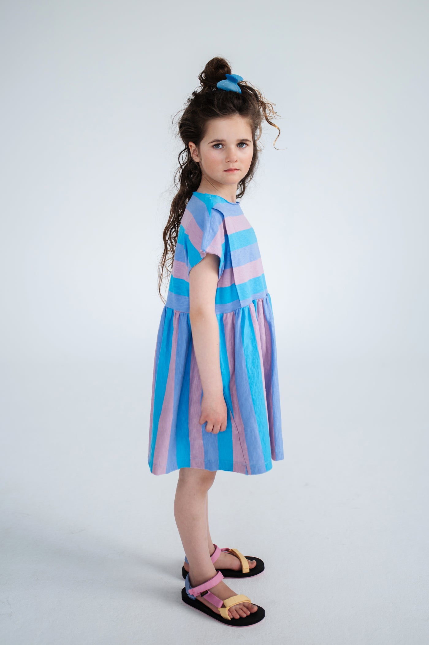 Tricolor block stripe dress made from 100% yarn-dyed organic cotton flamé. Features pleated front details, ruffled waist, side pockets, short sleeves, and raw edge neckline. A lightweight and comfortable dress for everyday wear