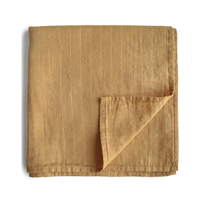 Cozy and soft organic cotton baby swaddle by Mushie in fall yellow color, ideal for swaddling, nursing, and cuddling. Made from 100% organic muslin cotton, gentle on baby’s skin, 120x120cm