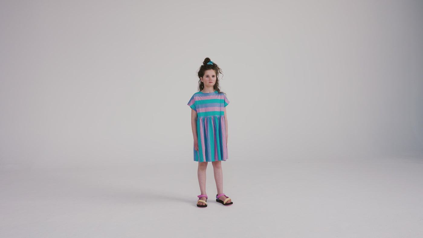 Tricolor block stripe dress made from 100% yarn-dyed organic cotton flamé. Features pleated front details, ruffled waist, side pockets, short sleeves, and raw edge neckline. A lightweight and comfortable dress for everyday wear.